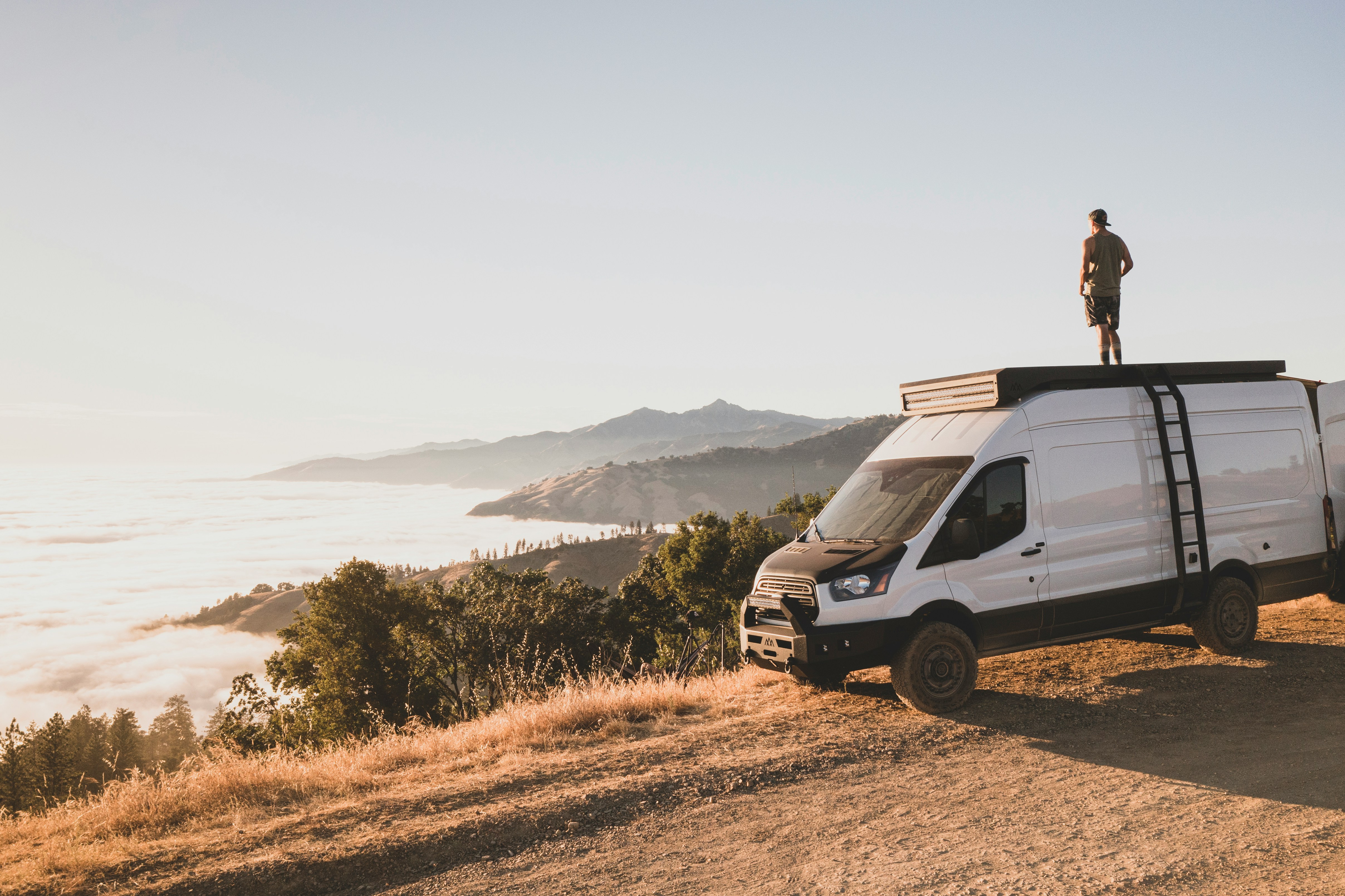 man in black jacket sitting on white van during daytime
