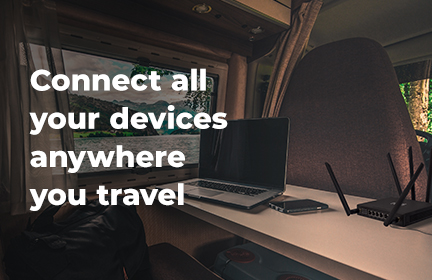 TravlFi JourneyXTR next to a laptop on a table in the inside of an RV with the caption "Connect all your devices anywhere you travel"